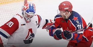 На изображении два хоккеиста в момент игры. Игрок в белой форме с изображением локомотива пытается отразить нападение, в то время как игрок в красной форме атакует его